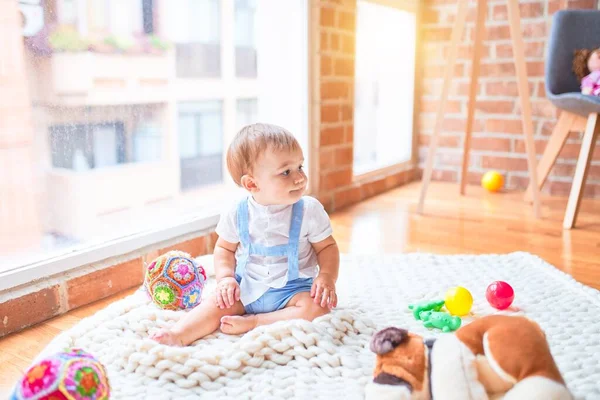 Anaokulunda Battaniyenin Üzerinde Bir Sürü Oyuncağın Etrafında Oturan Güzel Çocuk — Stok fotoğraf