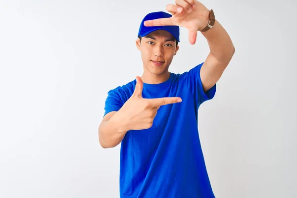 中国送货员穿着蓝色的T恤衫 头戴一顶帽子 站在孤立的白色背景上 微笑着 用双手和手指制作出笑脸的框架 创意和摄影概念 — 图库照片
