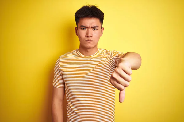 年轻的亚裔男子穿着T恤 站在孤立的黄色背景上 看起来很不高兴 很生气 带着拒绝和负面的手势 不好的表达方式 — 图库照片