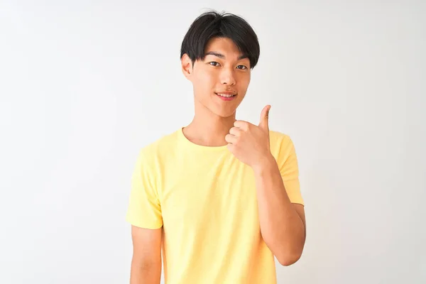 黄色のカジュアルなTシャツを着た中国人男性が孤立した白い背景の上に立って手で幸せな親指をジェスチャーを行います 成功を示すカメラを見て表現を承認する — ストック写真