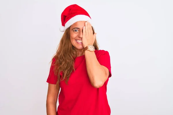 中年成熟した女性身に着けていますクリスマス帽子上の隔離された背景カバー一つ目で手 自信に満ちた笑顔上の顔と驚きの感情 — ストック写真