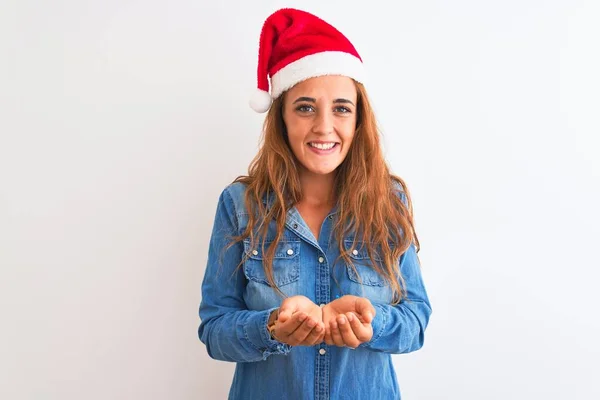 年轻美丽的红头发女人 头戴圣诞礼帽 背景孤寂 双手合十 微笑着接受或给予的姿态 扣留和保护 — 图库照片