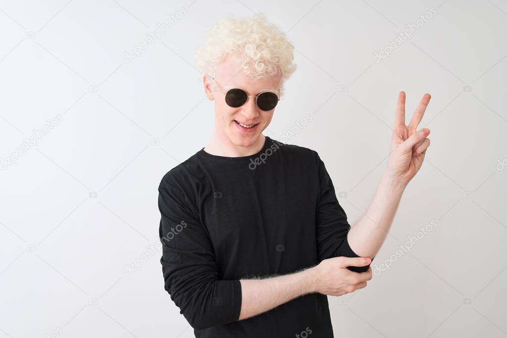 Young albino man wearing black t-shirt and sunglasess standing over isolated white background smiling with happy face winking at the camera doing victory sign. Number two.