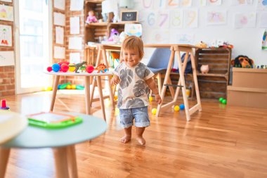 Anaokulunda bir sürü oyuncakla oynayan sevimli bir çocuk.