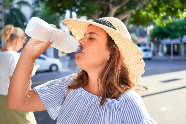 夏の晴れた日に新鮮な水を飲んで街の通りを歩く幸せな笑顔の若い美しい女性 — ストック写真