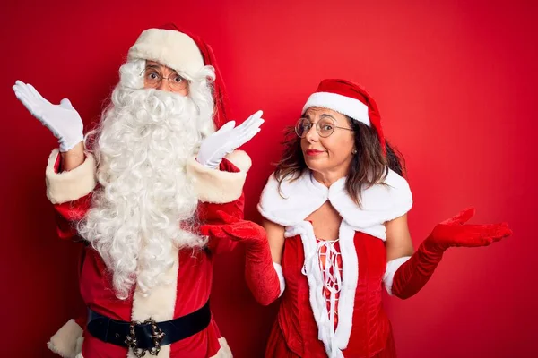 Paar Mittleren Alters Weihnachtsmannkostüm Und Brille Vor Isoliertem Roten Hintergrund — Stockfoto