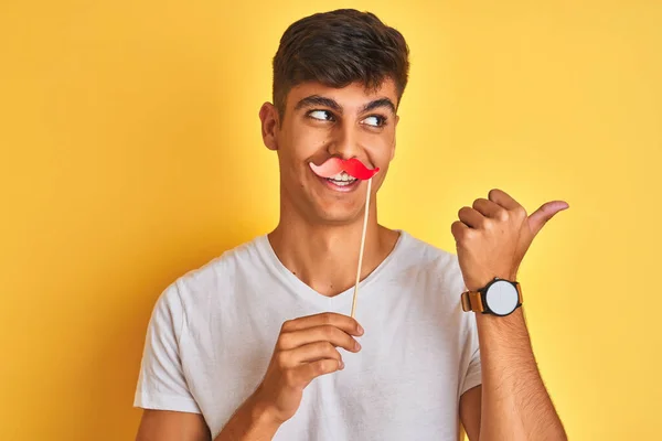 Young Indian Man Holding Fanny Mustache Standing Isolated Yellow Background — Stock Photo, Image