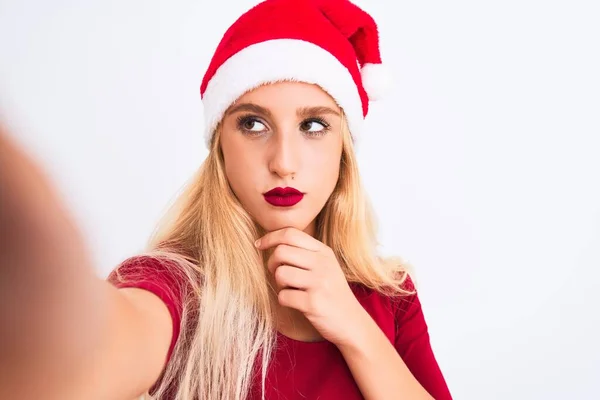 戴着圣诞圣诞圣诞礼帽的女人用相机在孤立的白色背景下自拍 严肃地思考问题 非常混乱的想法 — 图库照片