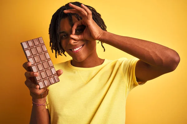Afro Američan Dredy Jíst Čokoládovou Tyčinku Přes Izolované Žluté Pozadí — Stock fotografie