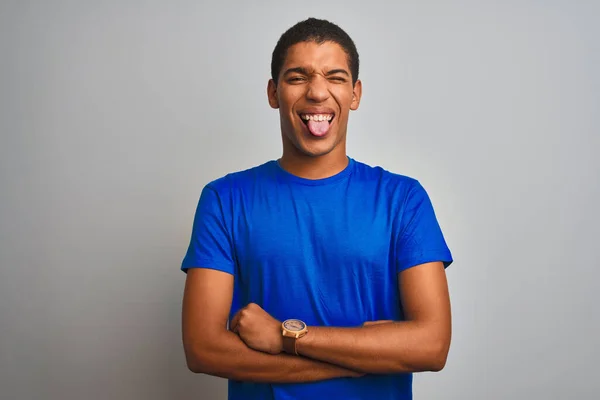 年轻英俊的阿拉伯男子穿着蓝色T恤 站在孤立的白色背景上 带着滑稽的表情伸出舌头 情感概念 — 图库照片