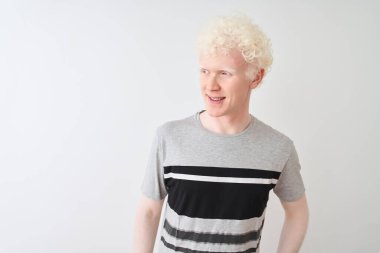 Genç albino sarışın adam izole beyaz arka plan üzerinde duran rahat t-shirt giyen yüzünde gülümseme, doğal ifade ile yan bakıyor. Gülmekten emin.