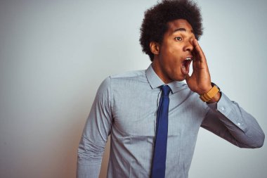 Afro saçlı, gömlekli ve kravatlı Amerikalı iş adamı izole edilmiş beyaz arka planda avazı çıktığı kadar bağırıyor ve ağızdan ağıza bağırıyordu. İletişim konsepti.