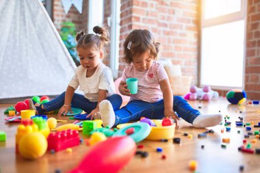 Anaokulunda plastik yemek ve çatal bıçak kullanarak yemek oynayan sevimli bebekler.