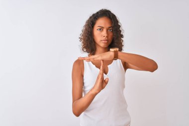 Brezilya 'lı genç bir kadın günlük tişört giyip izole edilmiş beyaz arka planda duruyor. Elleriyle, hayal kırıklığına uğramış ve ciddi bir yüz ifadesiyle jest yapıyor.