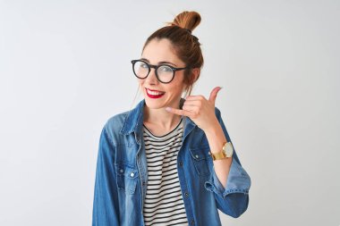 Çizgili tişört ve gözlük takan kızıl saçlı kadın izole edilmiş beyaz arka planda gülümsüyor telefonla el ve parmak hareketleri yapıyor telefonda konuşuyor gibi. İletişim kavramları.
