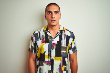 Beyaz tenli, yaz tişörtü giymiş genç bir adam korku, korku ve heyecan dolu bir yüz ifadesiyle korkmuş ve şok olmuştu..