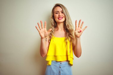 Young beautiful woman wearing yellow t-shirt standing over white isolated background showing and pointing up with fingers number nine while smiling confident and happy.