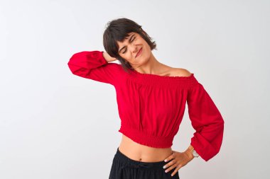 Kırmızı yaz tişörtü giyen genç ve güzel bir kadın izole edilmiş beyaz arka planda dikiliyor boynu ağrıyor, eliyle boynuna dokunuyor, kas ağrısı çekiyor.