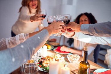 Aile ve arkadaşlar geleneksel yemek ve dekorasyonla Noel arifesini evde kutluyor, bir kadeh şarapla en iyi dileklerimizi sunuyorlar.