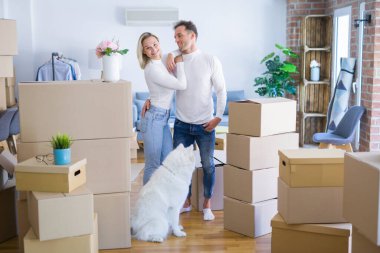 Karton kutular etrafında yeni evde duran köpek ile genç güzel çift