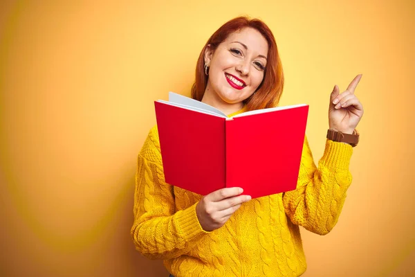 Молодая Рыжая Учительница Читающая Красную Книгу Желтом Изолированном Фоне Довольна — стоковое фото