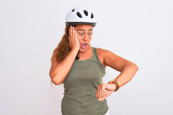 中年成熟的骑自行车的女人 戴着安全帽 背景偏僻 看着钟表时间焦急 害怕迟到 — 图库照片