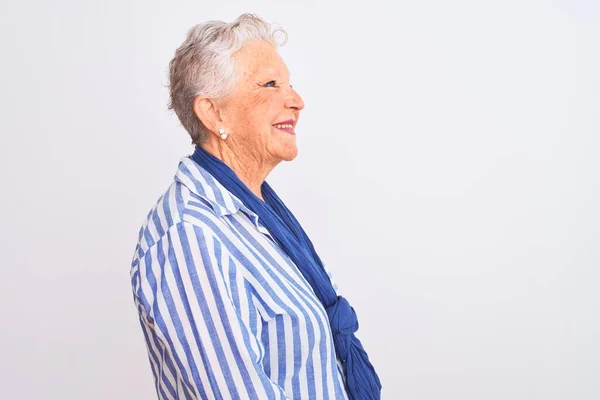 高个子灰发女人穿着蓝色条纹衬衫 站在孤零零的白色背景上观望 带着自信的微笑放松自己的姿态 — 图库照片