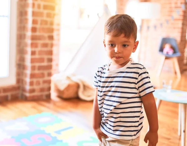 漂亮的蹒跚学步的男孩站在幼儿园 手里拿着很多玩具 — 图库照片