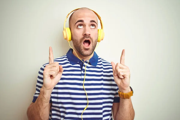 Joven Escuchando Música Con Auriculares Amarillos Sobre Fondo Aislado Asombrado —  Fotos de Stock