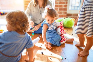 Güzel öğretmen ve bir grup çocuk anaokulunda bir sürü oyuncakla oynuyorlar.
