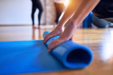 Spor salonunda yoga yapmak için spor minderi kullanan genç ve güzel bir sporcu.