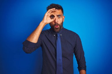 Zarif gömlek ve kravat giyen genç Hintli işadamı mavi arka planda dikiliyordu. Şaşırmış yüz ifadesiyle, parmaklarından bakarak şok olmuştu. İnançsız ifade.