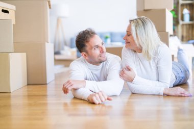 Karton kutuların etrafındaki yeni evde yere uzanmış genç ve güzel bir çift.