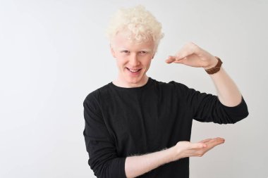 Siyah tişört giyen genç albino adam izole edilmiş beyaz arka plan üzerinde duruyor. Ellerinde büyük ve büyük boy işareti var. Ölçüm sembolü. Kameraya bakıp gülümsüyor. Ölçüm konsepti.
