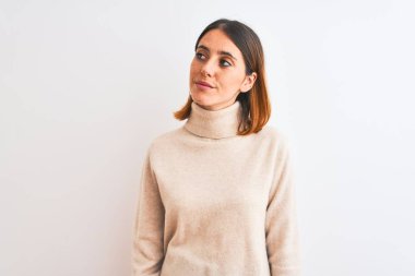 Kış balıkçı yaka kazak giyen güzel kızıl saçlı kadın izole edilmiş arka planda gülümsüyor ve uzaklara bakıp düşünüyor..