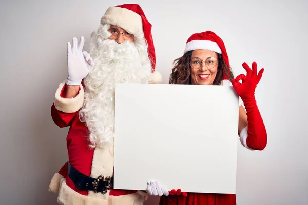 上了年纪的夫妻穿着圣诞老人的服装 手握横幅 挂在孤独的白色背景上 手握大旗 手握大棒 象征非凡 — 图库照片