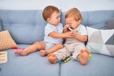 Kanepede oturup evde oyuncaklarla oynayan güzel bebekler.