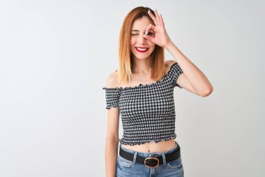 Güzel kızıl saçlı kadın rahat t-shirt üzerinde ayakta giyen izole beyaz arka plan ile ok jest yapıyor el gülümseyen, göz görünümlü parmaklar ile mutlu yüz.