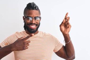 Çizgili tişört ve gözlük takan Afro-Amerikan bir adam izole edilmiş beyaz arka planda gülümsüyor ve kameraya bakıp iki eliyle ve parmaklarıyla yan tarafı işaret ediyor..