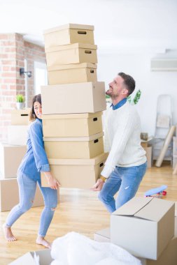 Genç güzel çift yeni evde karton kutu yığını tutan