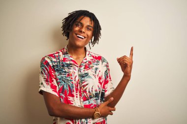 Tatilde saçlarını örten Afro saçlı bir adam izole edilmiş beyaz arka planda, yüzünde kocaman bir gülümsemeyle kameraya bakan eli ve parmağı olan bir adam..