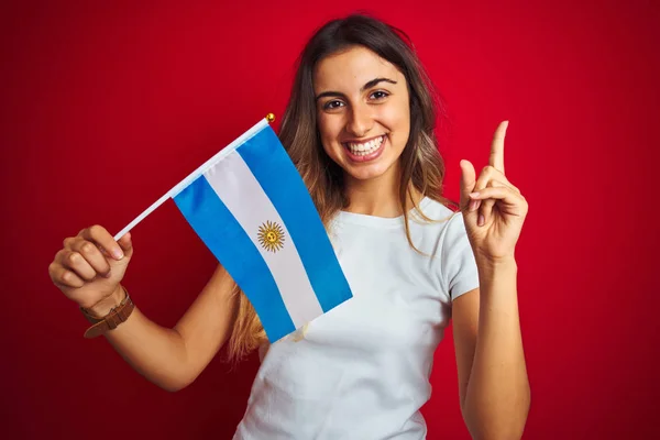 Joven Hermosa Mujer Sosteniendo Bandera Argentina Sobre Fondo Rojo Aislado — Foto de Stock