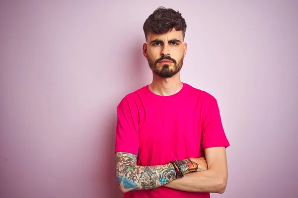 Fiatal Férfi Tetovált Pólóban Áll Izolált Rózsaszín Háttér Szkeptikus Ideges — Stock Fotó