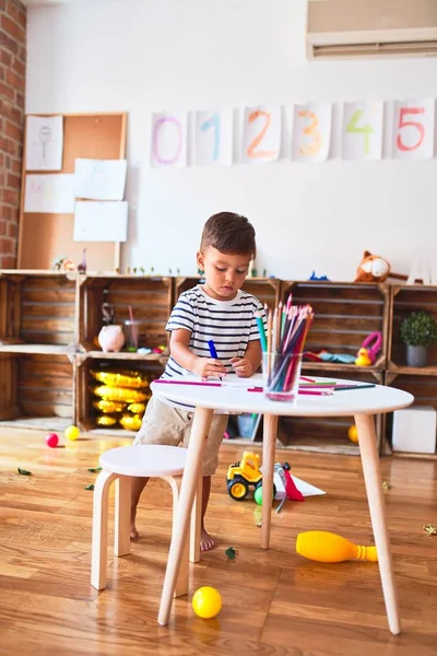 美しい幼児の男の子は幼稚園で色鉛筆を使ってかわいい絵を描く — ストック写真