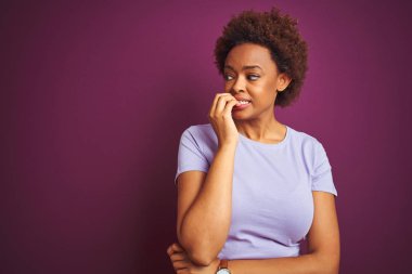 Afro saçlı, yalnız mor arka planı olan genç ve güzel Afro-Amerikalı kadın elleri ağız yiyen tırnaklarıyla gergin ve stresli görünüyor. Endişe sorunu.