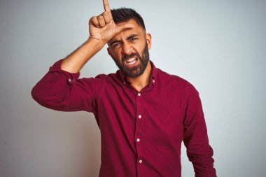 Kırmızı şık gömlekli genç adam gri arka planda dikiliyor. Alnında parmakları olan insanlarla dalga geçiyor. Ezik hareketler yapıyor, alay ediyor ve hakaret ediyor..