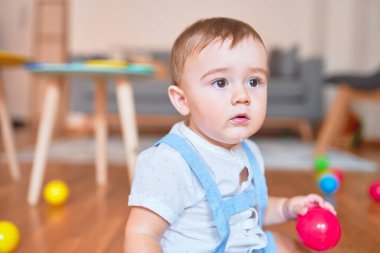Anaokulunda küçük renkli toplarla oynayan güzel bir çocuk.
