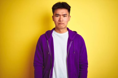 Mor kazak giyen Asyalı genç adam izole edilmiş sarı arka planda duruyor. Depresyonda ve endişe içinde, sinirli ve korkmuş. Üzücü ifade.