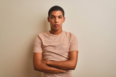 İzole edilmiş beyaz arka plan üzerine çizgili tişört giyen yakışıklı Arap adam yüzünde ciddi bir ifadeyle. Basit ve doğal bir şekilde kameraya bakıyorsun..