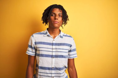 Sarı arka plan üzerinde çizgili tişört giyen Afro-Amerikan bir adam depresif ve endişeli, sinirli ve korkmuş. Üzücü ifade.